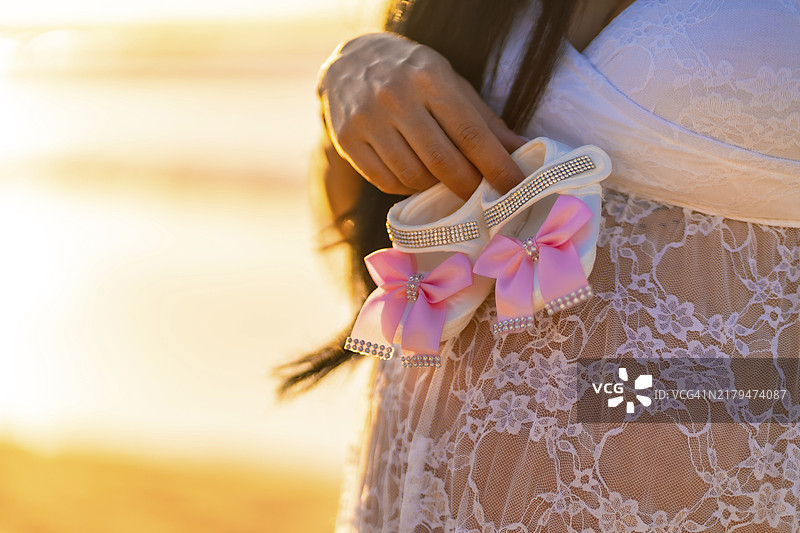 一位女士手持粉白色婴儿鞋，期待新生命的到来图片素材