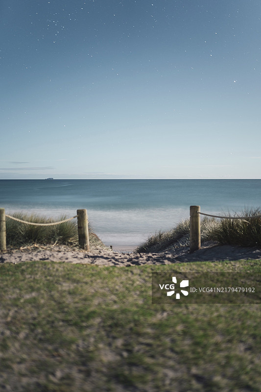 宁静海滩和海洋之上的星夜，由木桩和绳索划分图片素材