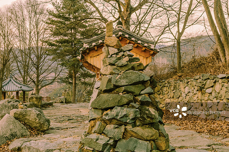韩国乡村路边公园的石制锥形塔和东方木制建筑图片素材