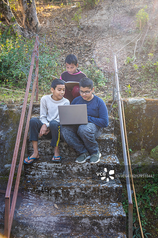 印度乡村儿童在乡村水泥楼梯上使用笔记本电脑图片素材