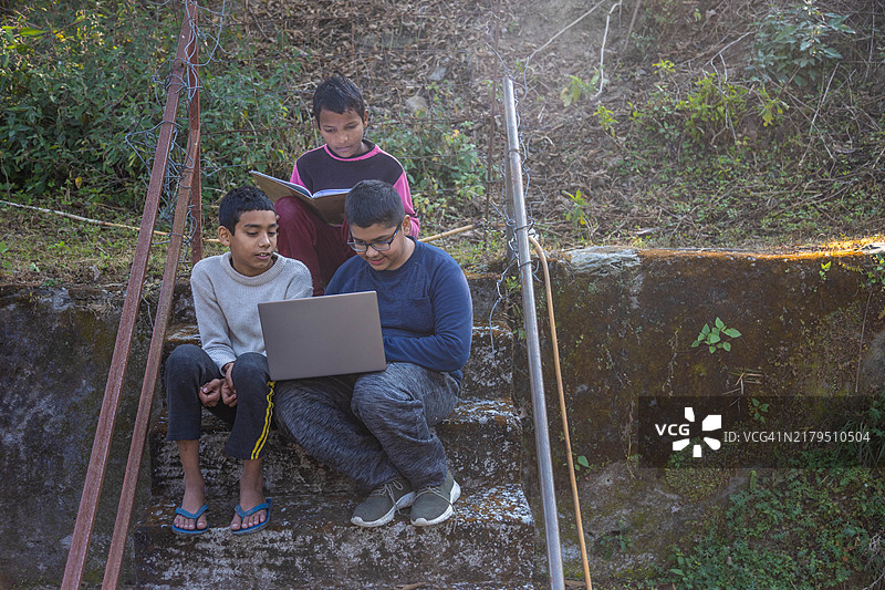 印度乡村儿童在乡村水泥楼梯上使用笔记本电脑图片素材