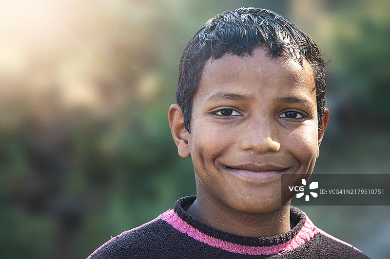 在印度乡村户外环境中对着镜头微笑的快乐印度男孩图片素材