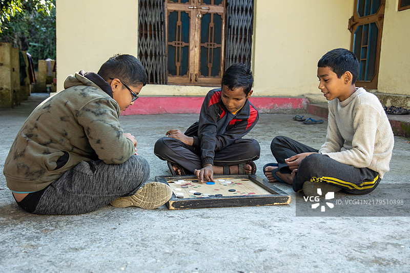 三个孩子在户外玩卡罗姆棋盘游戏图片素材