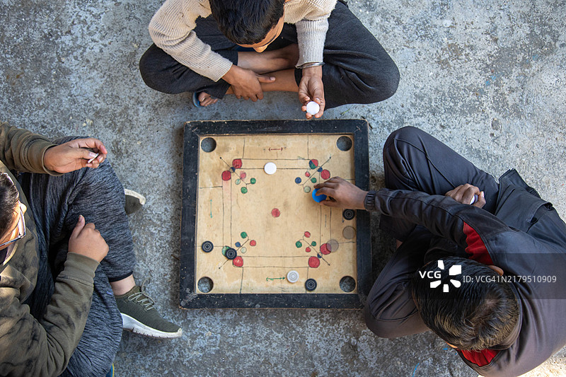 三个孩子在户外玩卡罗姆棋盘游戏图片素材