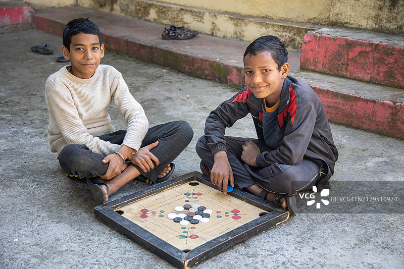 两个孩子在户外玩卡罗姆棋盘游戏图片素材