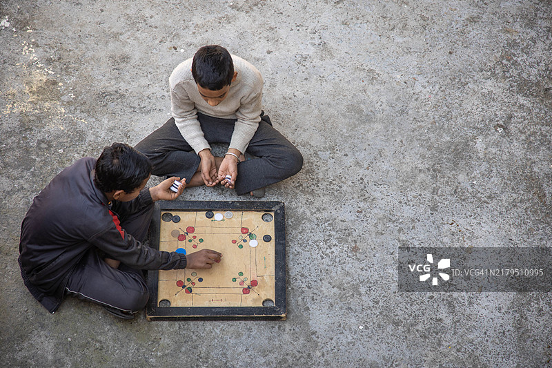 两个孩子在户外玩卡罗姆棋盘游戏图片素材