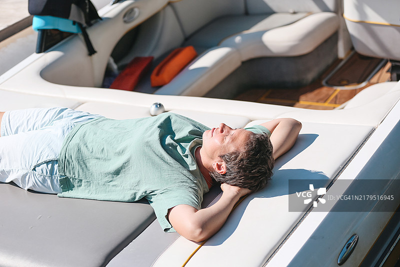 中年女性冲浪者在阳光明媚的夏日里放松并在船上小憩图片素材