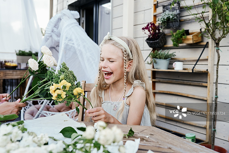 金发美女和妈妈在鲜花装饰的屋顶露台上玩耍图片素材