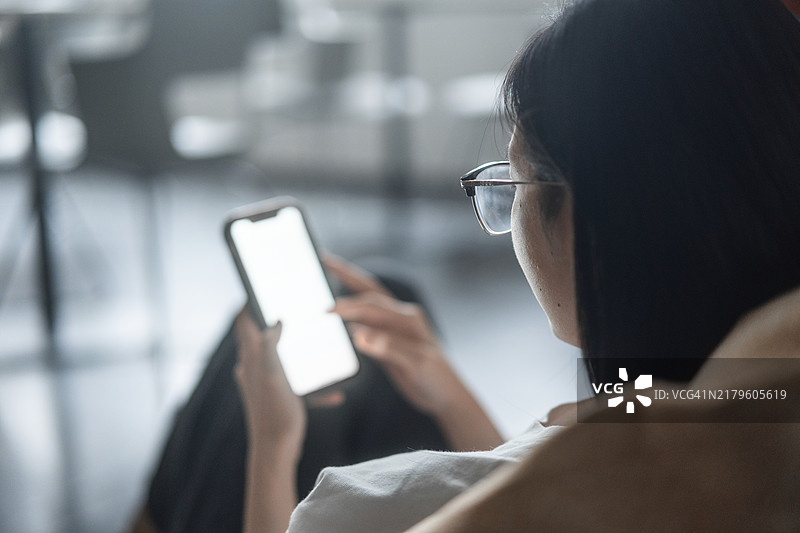 亚洲女性在办公室使用智能手机图片素材