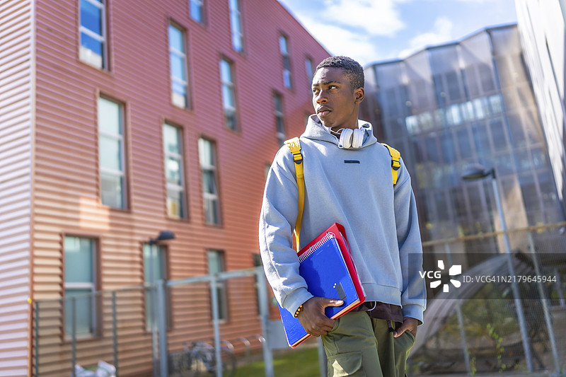 穿着连帽衫和都市服装自信地站在大学外的非洲学生图片素材