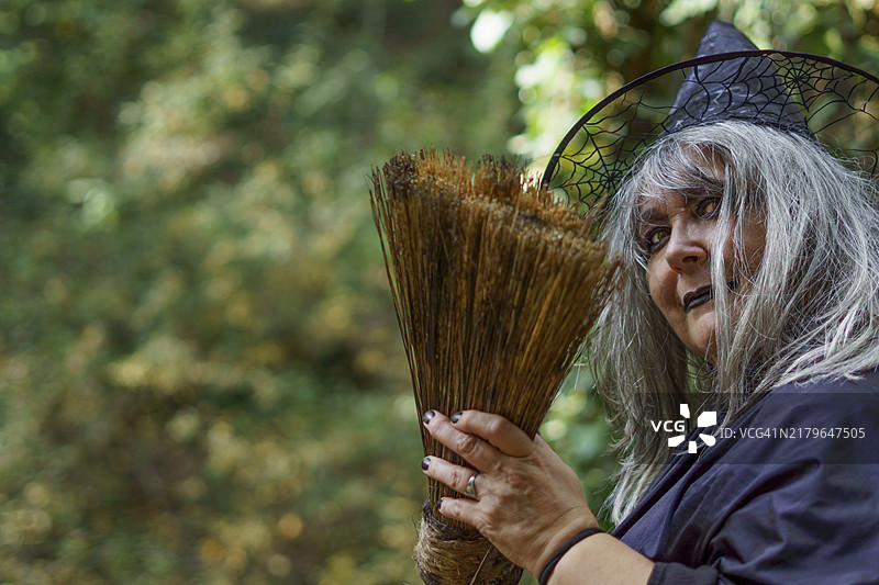 手持扫帚微笑的白发黑帽老女巫图片素材