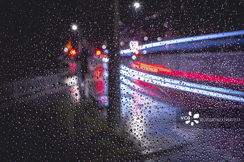 雨天窗格：德国图林根耶拿，黑暗中行驶车辆的模糊光迹图片素材