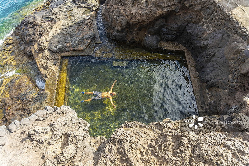 在西班牙加那利群岛拉帕尔马岛蓬塔戈尔达港海湾的天然海池中享受的年轻人图片素材