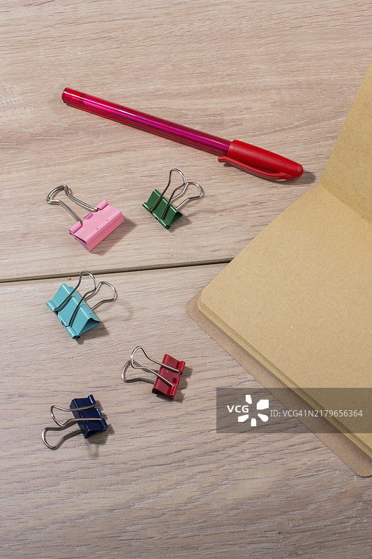木纹上的棕色笔记本、笔和回形针图片素材