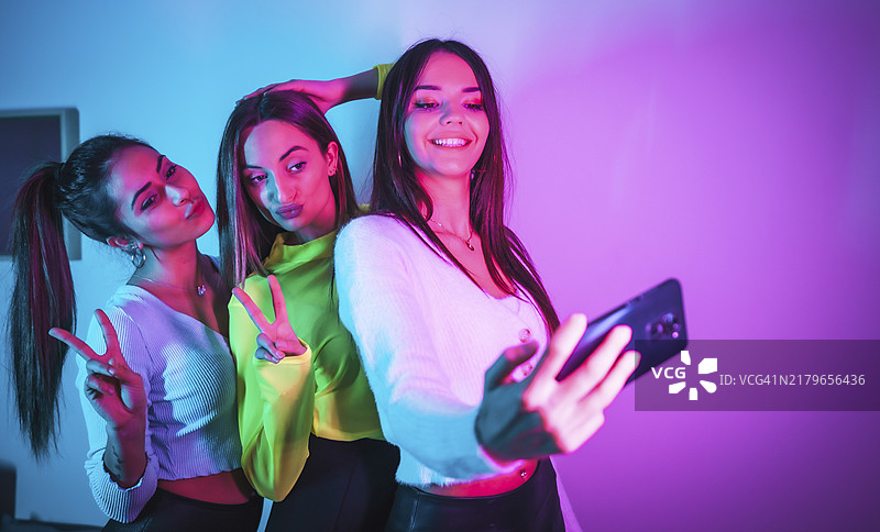 朋友们在迪斯科舞厅聚会，用手机拍照分享到社交网络图片素材