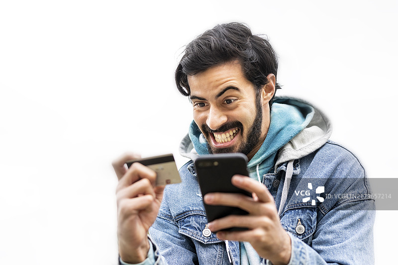 拉丁裔男人使用信用卡在智能手机上进行在线支付图片素材