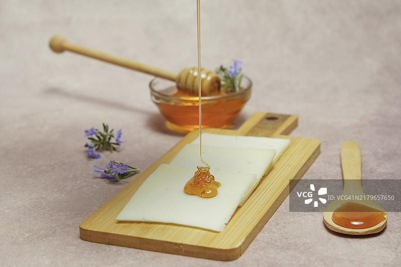 蜂蜜滴在奶酪片上，配以新鲜迷迭香枝和迷迭香蜂蜜玻璃碗图片素材