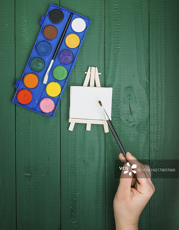手持画笔、迷你画架和水彩调色板的高视角图图片素材