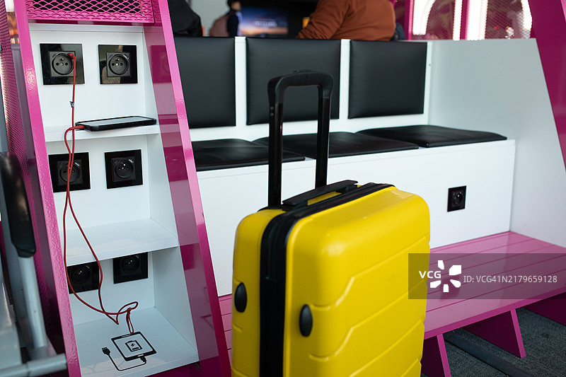 机场充电站旁的黄色行李箱，手机正在充电，便捷出行瞬间图片素材