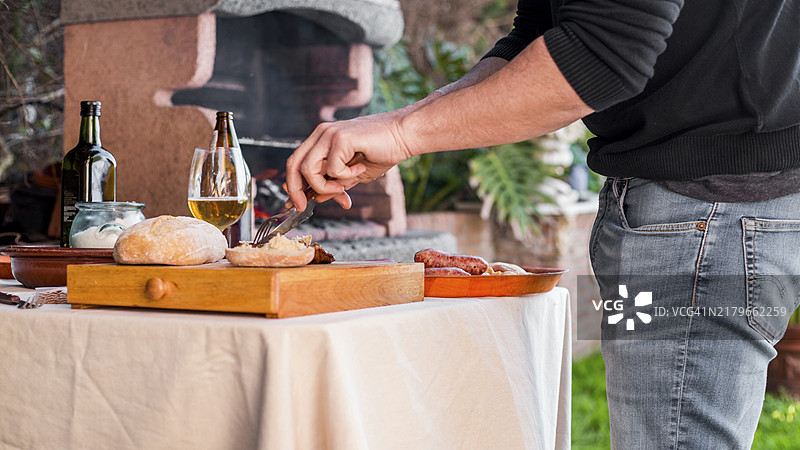 男人在户外用刀叉切烤鸡面包图片素材