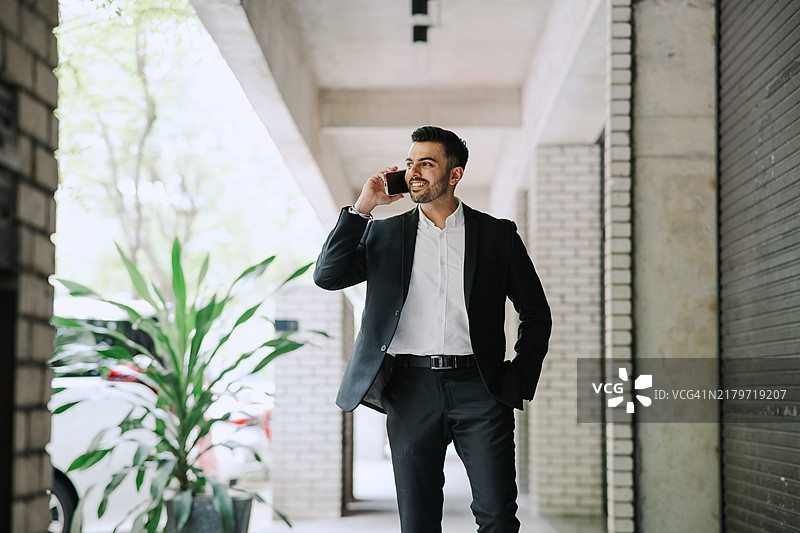 在金融大厦外用智能手机交谈的印度裔商人图片素材