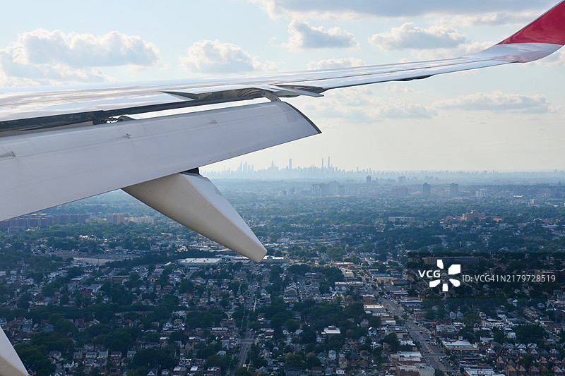 飞机飞过郊区，背景是纽约市天际线图片素材
