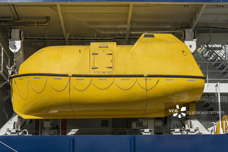 可容纳六十人的黄色封闭式救生艇悬挂在船上的吊艇架上图片素材