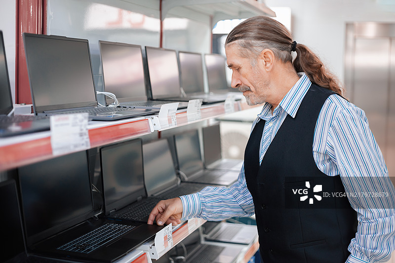 男人在电子商店检查笔记本电脑图片素材
