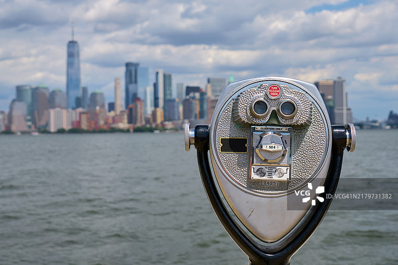从自由岛指向纽约市天际线的投币式望远镜图片素材