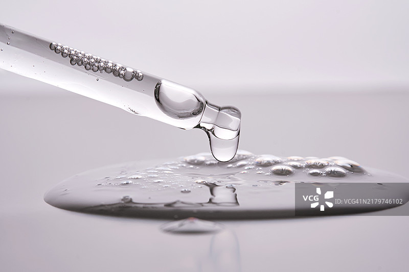滴管精华液，背景是清晰展示产品质地的水滴图片素材