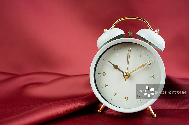 红色纺织背景上的复古风格绿色金色钢制闹钟图片素材