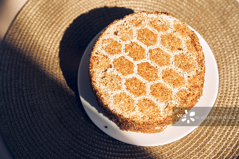 桌子上放着餐巾和阳光的蜂蜜蛋糕。俯视图。图片素材