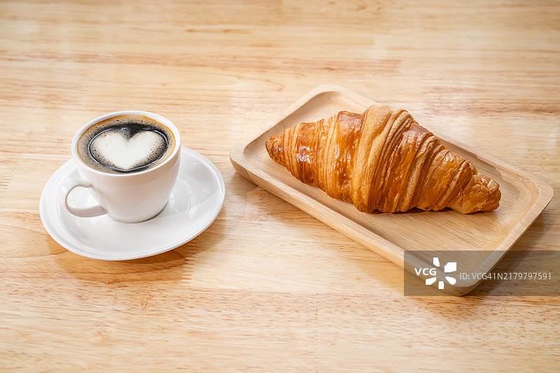 咖啡杯和新鲜牛角面包，木质背景，舒适美味的早餐图片素材
