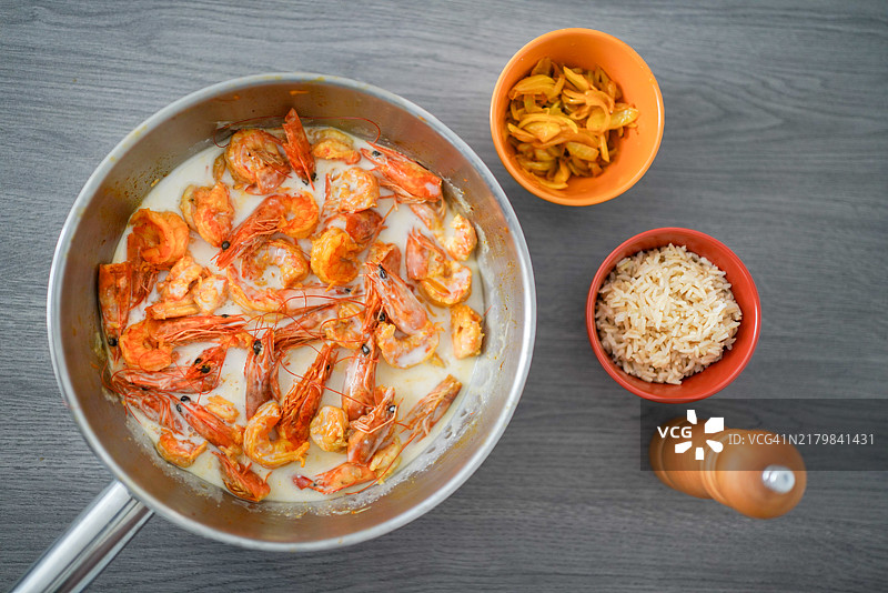 椰奶奶油蒜香虾，配有米饭、薯片和胡椒磨的碗。图片素材
