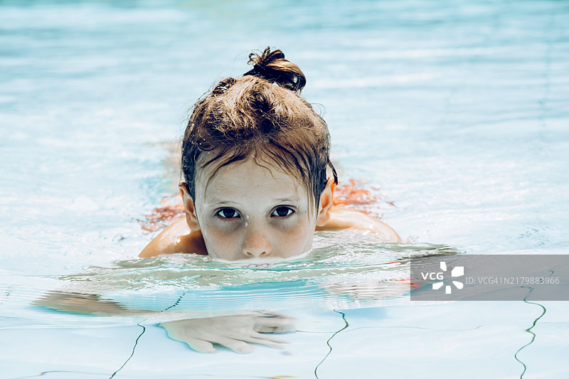 在泳池中漂浮的有趣马尾男孩游泳者画像图片素材