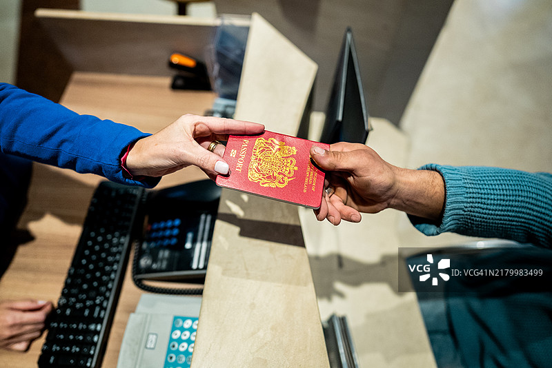 顾客将护照递给酒店接待员的特写镜头图片素材