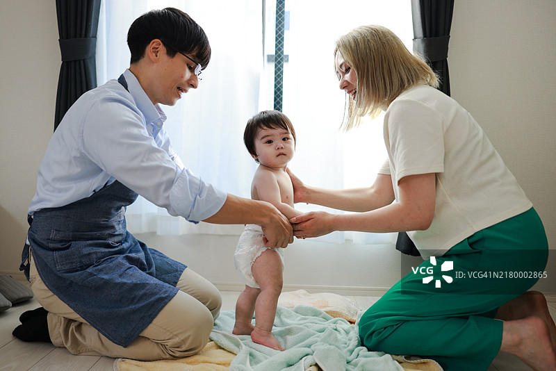 父母为宝宝换尿布图片素材