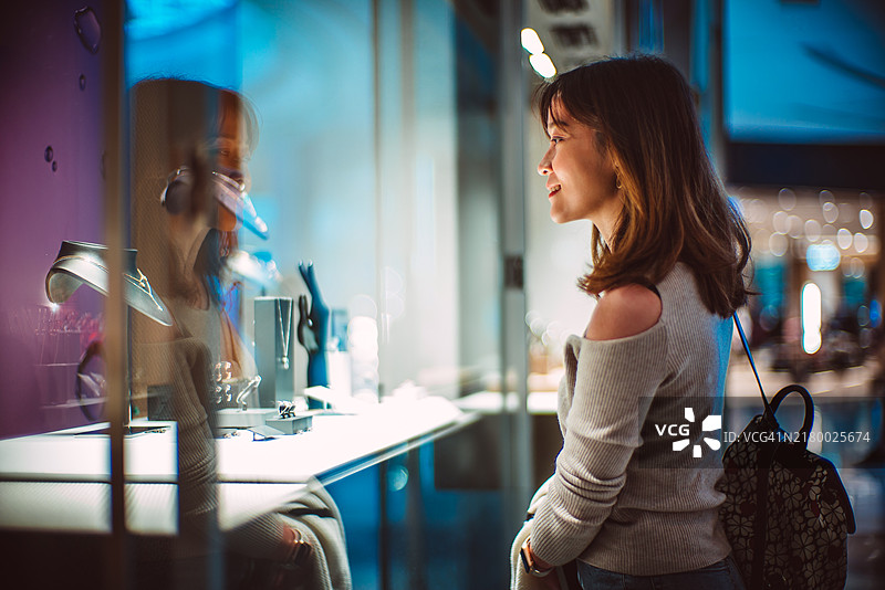 年轻的亚洲女性在购物中心橱窗购物图片素材