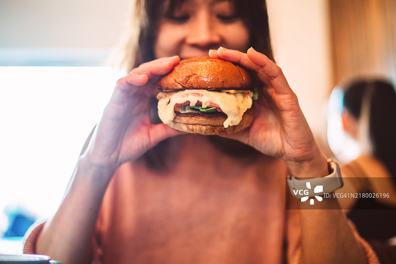 女人在当地餐厅享用美食汉堡图片素材