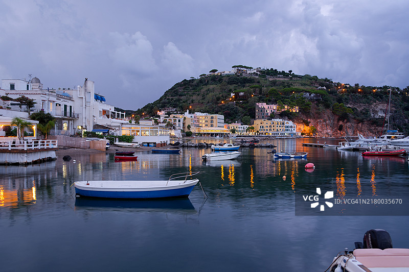 意大利伊斯基亚岛拉科阿梅诺港口夜景：水边餐厅灯火辉煌，船只停靠在码头图片素材