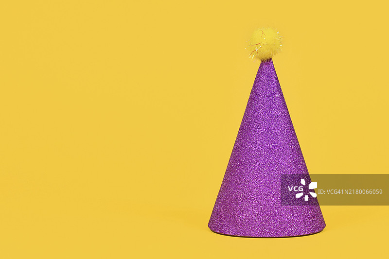 黄色背景上的紫色闪光派对帽（含文案空间）图片素材