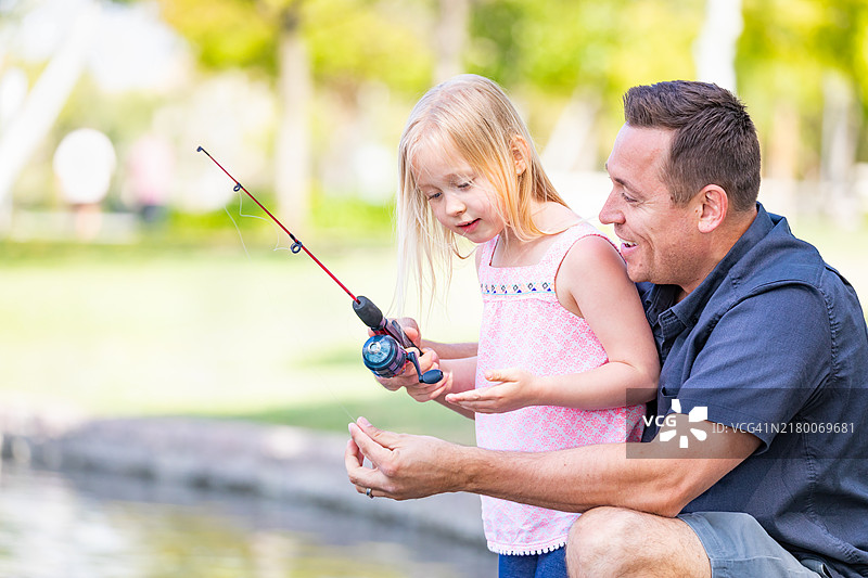 年轻的白人父女在湖边钓鱼图片素材