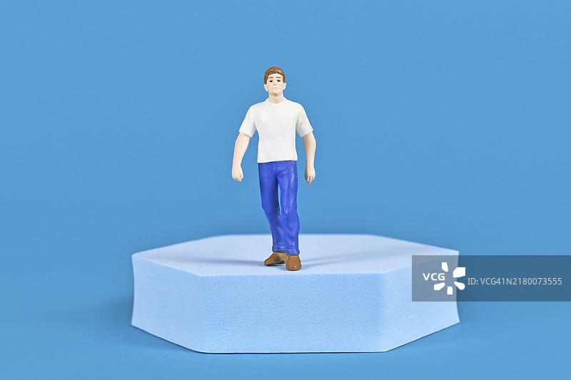 衬衫牛仔裤人偶在蓝色背景前的基座上图片素材