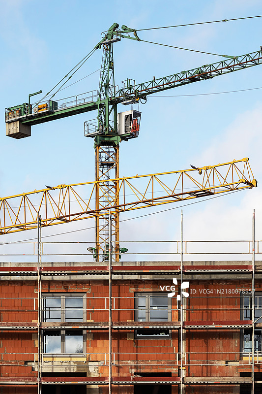 带有脚手架和大型起重机的住宅楼施工现场图片素材