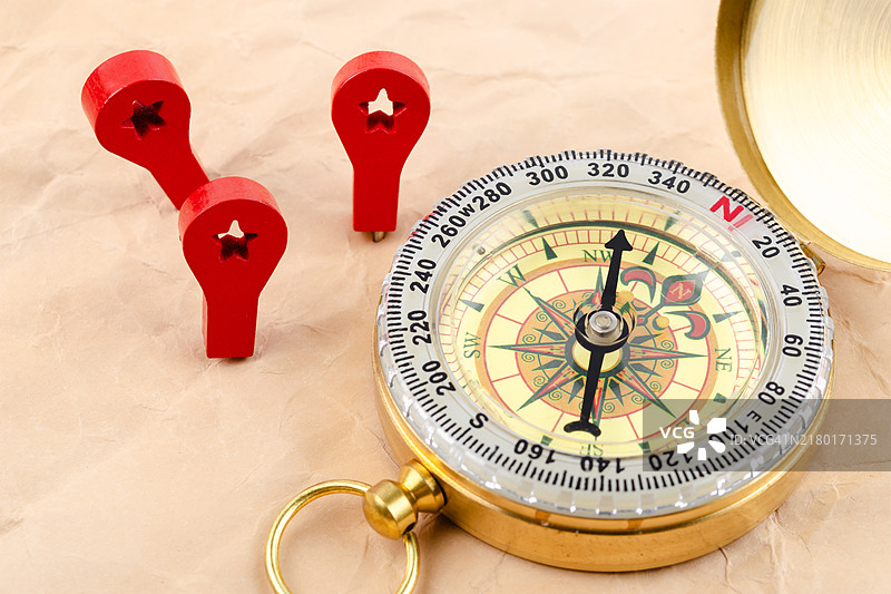棕色背景上带有红色木制图钉的金色古董指南针图片素材