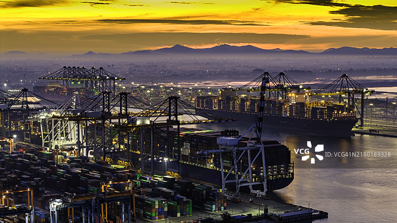 航拍视角：集装箱货轮停靠码头，通过起重机装载集装箱，用于物流运输图片素材