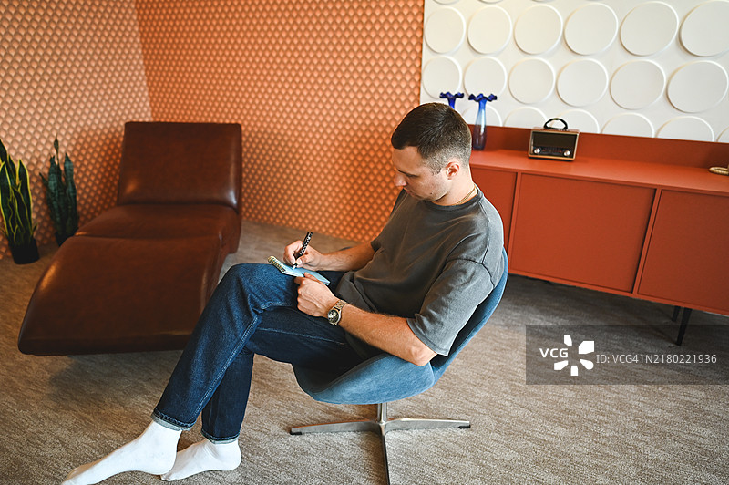 中年男人坐在椅子上用笔写作图片素材