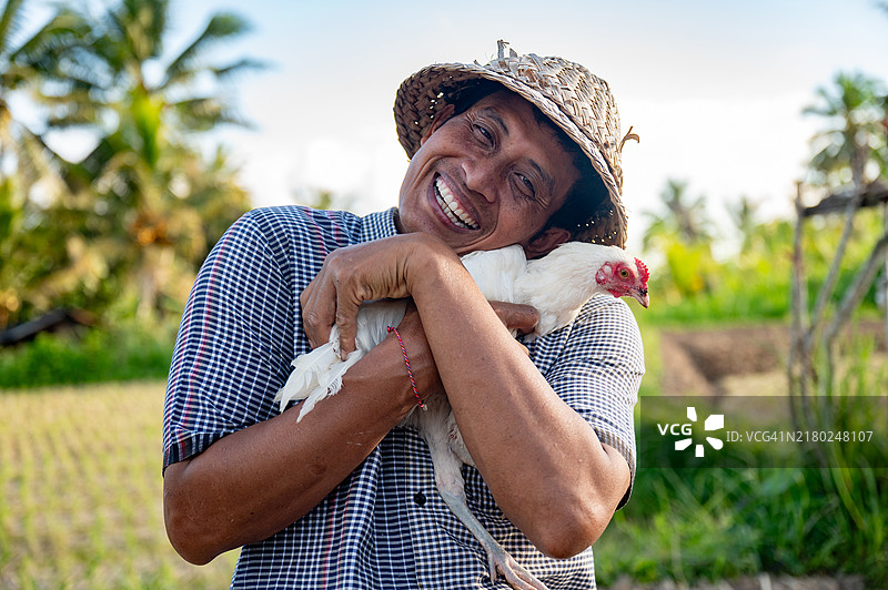 快乐的亚洲农民抱着一只鸡微笑图片素材