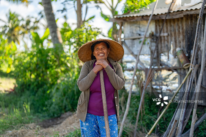 在屋外拿着扫帚微笑的亚洲女人图片素材