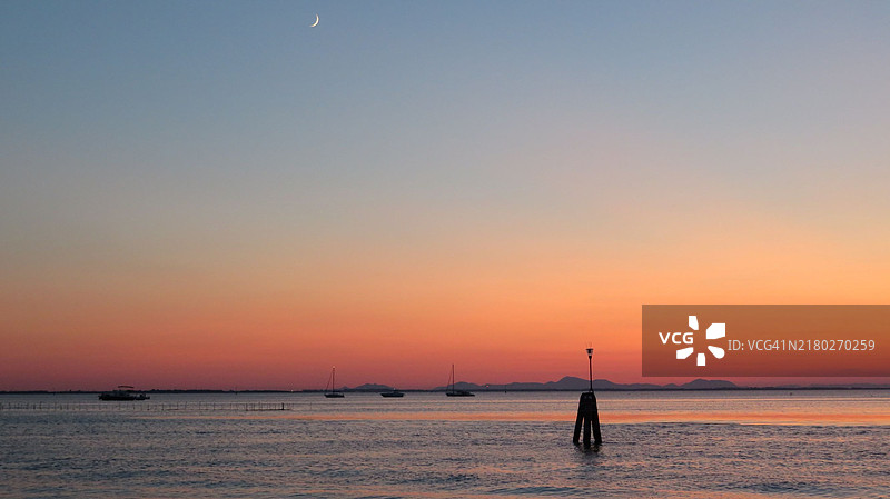 日落时分，海滩上站着的男人剪影与天空相映成趣图片素材